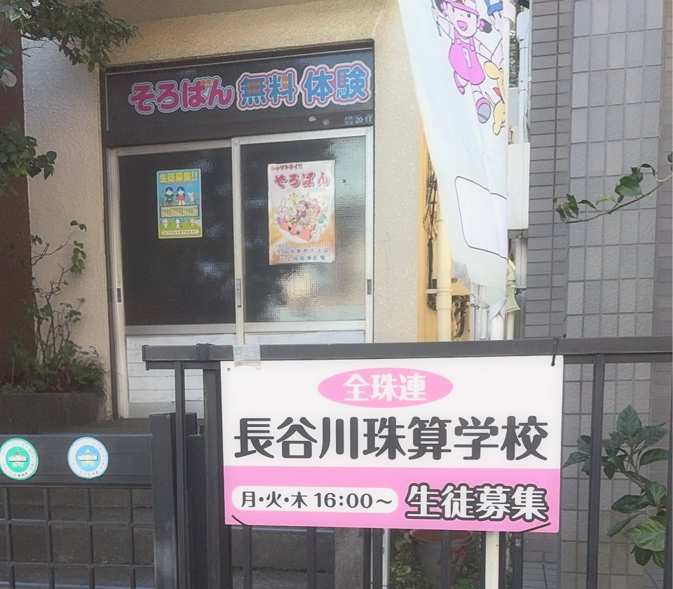 長谷川珠算学校の外観。「そろばん 無料体験」の看板と、ピンク色の入口看板